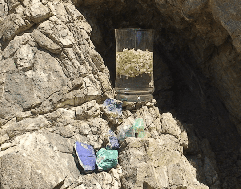 A glass of water is sitting on the rocks.